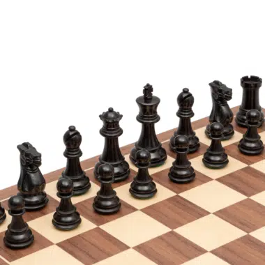 Pièces d'échecs noires en bois de buis alignées sur l'échiquier noyer et érable