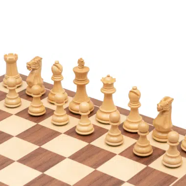 Pièces d'échecs blanches en bois de buis alignées sur l'échiquier noyer et érable