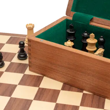 Coffret bois de rose ouvert avec pièces noires et blanches rangées sur feutrine verte