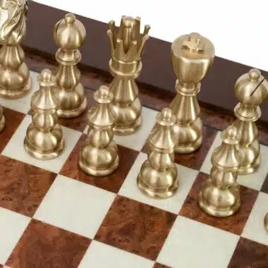 Pièces d'échecs en laiton doré disposées sur l'échiquier en bois marqueté