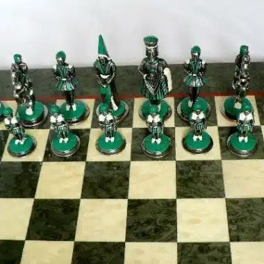 Rangée de pièces vertes Camelot alignées sur l'échiquier en érable olive
