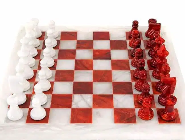 Pièces blanches et rouges en marbre face à face sur l'échiquier