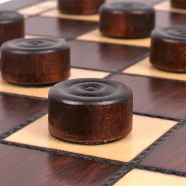 Jeu de dames en bois, pions foncés disposés sur les cases claires de l'échiquier