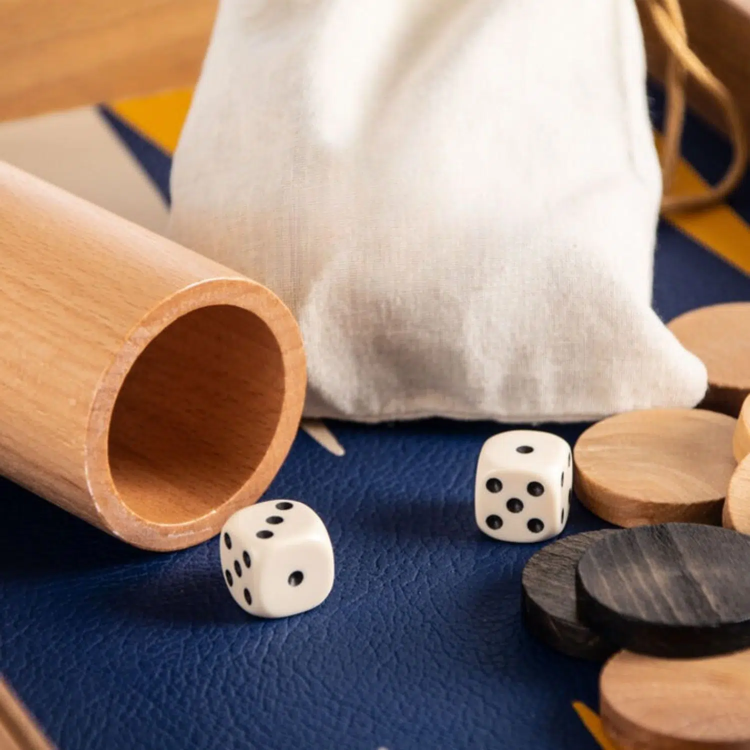 Gros plan sur les dés blancs et les pions bois posés sur le similicuir bleu