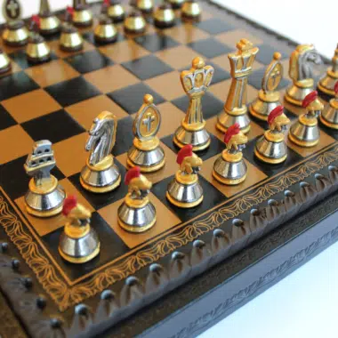 Gros plan sur les pièces d'échecs romaines en métal sur l'échiquier en similicuir noir et or