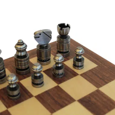Détail des pièces d'échecs contemporaines couleur argent sombre posées sur l'échiquier en acajou et érable