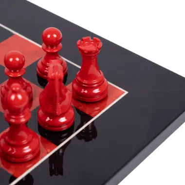 Gros plan sur les pièces d'échecs rouges laquées et la finition miroir de l'échiquier