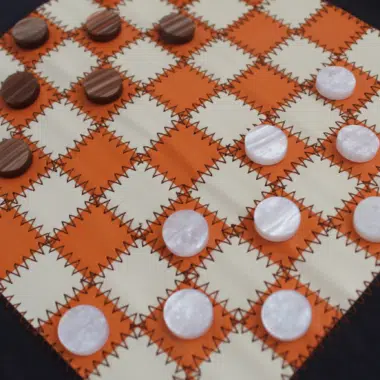 Plateau du jeu de dames sur tapis souple orange et crème avec jetons marbrés
