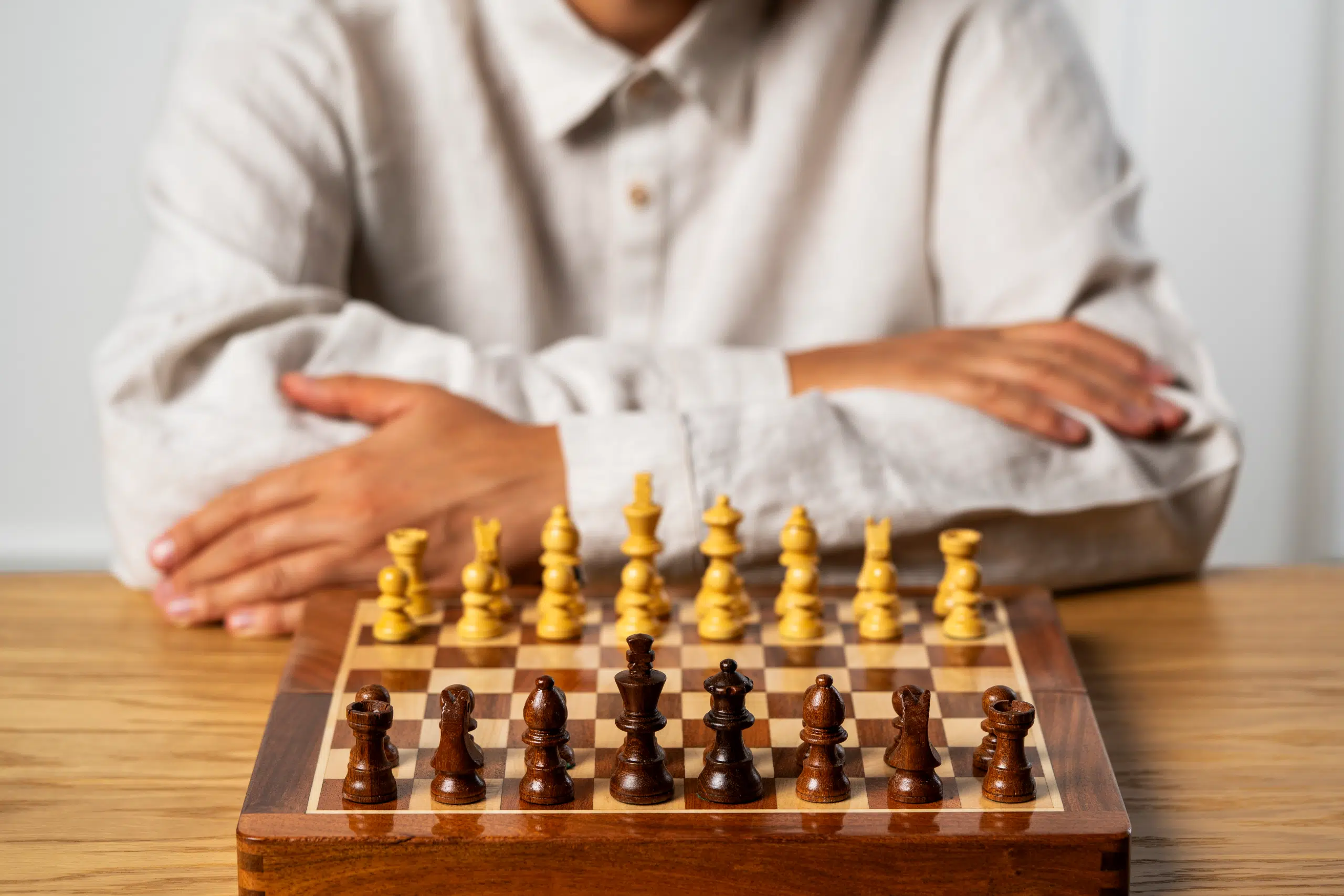Jeune joueur avec jeu d'échecs en bois sur une table, prêt à commencer une partie - Le Palais Des Echecs